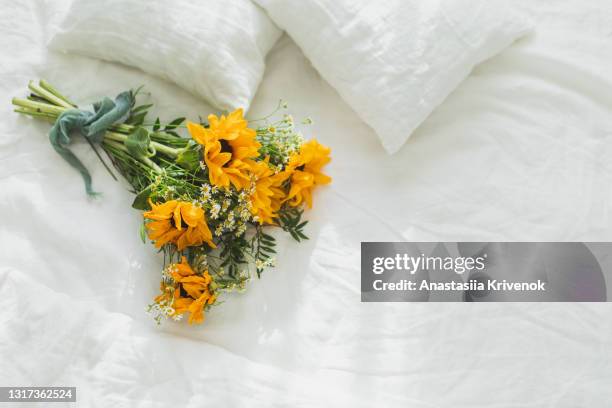 bouquet of wildflowers lying on white linen bed. - blumenstrauß stock-fotos und bilder