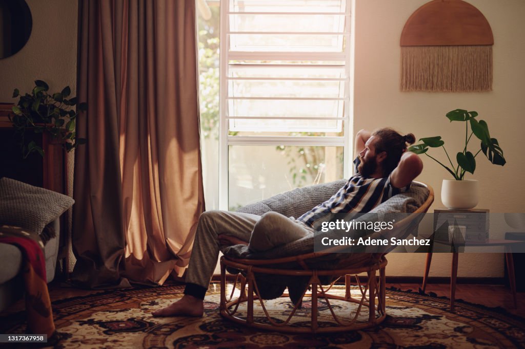 Tiro de um jovem relaxando em uma cadeira em casa