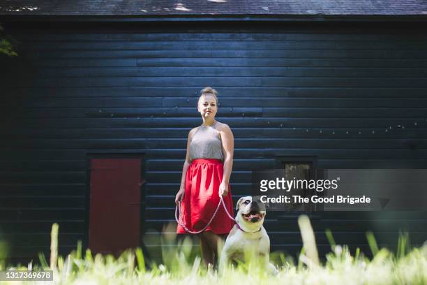 portrait of young woman wearing red skirt with dog - rock dog stock-fotos und bilder