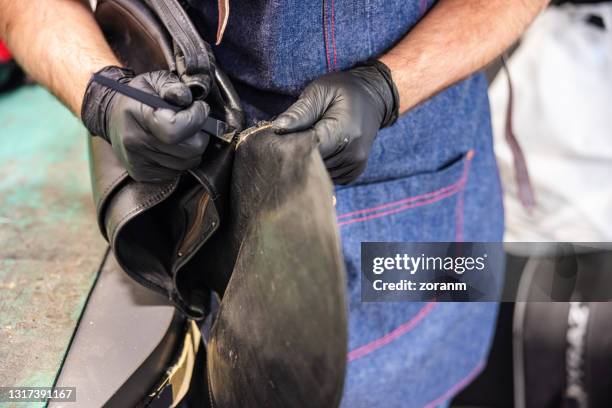 wearing protective gloves and using chisel to tear seam on leather item - leather bag stock pictures, royalty-free photos & images