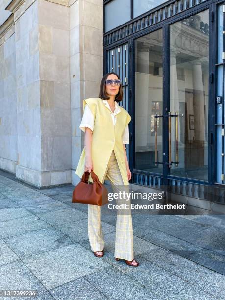 Gosia Boy @gosiaboy wears sunglasses, a white shirt with short sleeves from Remain by Birger Christensen, a pale / pastel yellow oversized sleeveless...