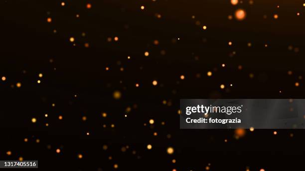 defocused golden particles against black background - bokeh lights fotografías e imágenes de stock