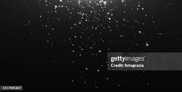 defocused white particles against black background - 雪　降る ストックフォトと画像