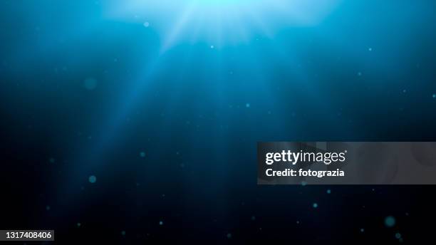 underwater background with sun rays and defocused particles - sea sunlight underwater stockfoto's en -beelden