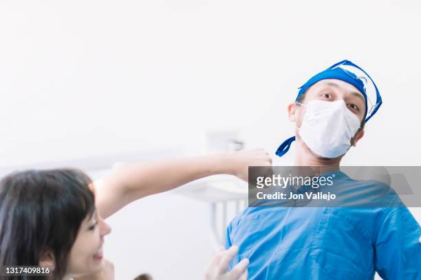 cuando el dentista y el paciente no se ponen de acuerdo, el paciente hace la broma de intentar golpear al dentista. - doctor paciente stockfoto's en -beelden