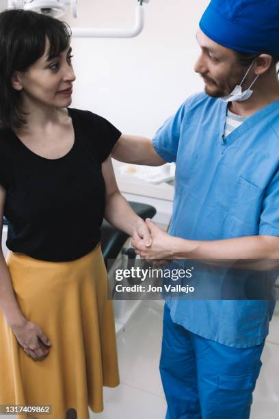 el dentista y el paciente se dan la mano tras acordar el tratamiento que se va a realizar. - doctor paciente stockfoto's en -beelden