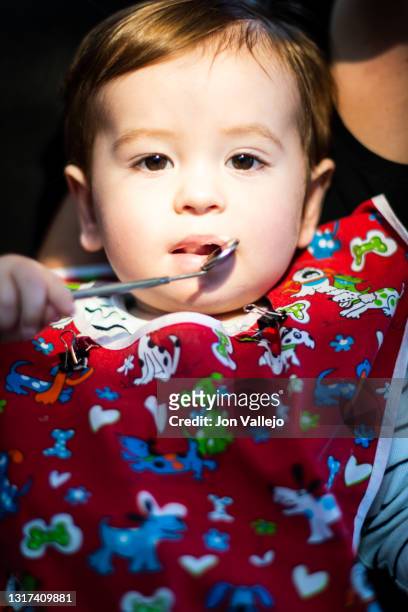 foto vertical de un niño de menos de dos años en la consulta del dentista con una bata roja, el niño se pone un pequeño espejo de dentista en la boca. - 35 39 años stock pictures, royalty-free photos & images