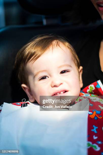 un niño de menos de dos años está en la consulta del dentista con una bata roja y un babero de palel. - 35 39 años stock pictures, royalty-free photos & images