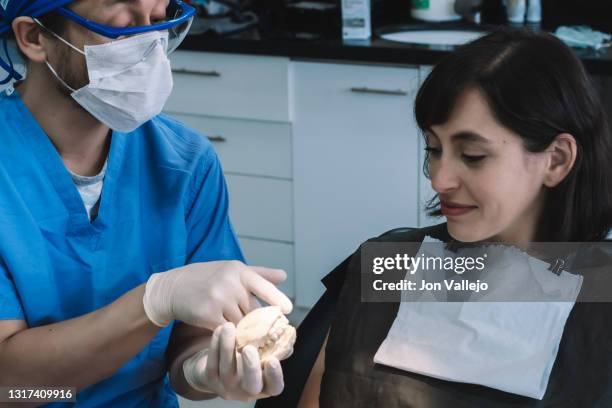 un dentista muestra a su paciente una escayola en su consulta. - escayola stock-fotos und bilder