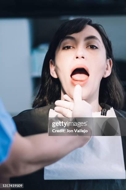 dentista abriendo la boca del paciente para observar los dientes. - doctor paciente stockfoto's en -beelden