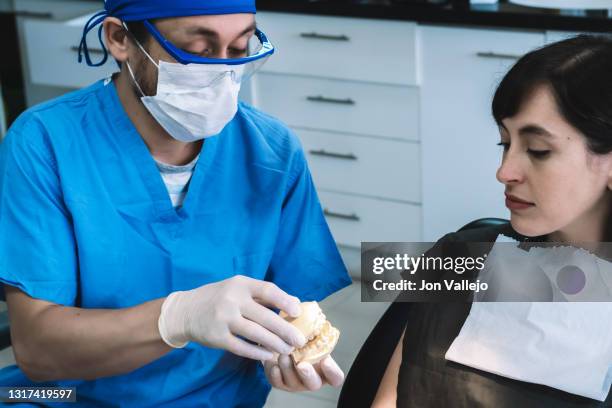 un dentista muestra a su paciente una escayola en su consulta. - escayola stock-fotos und bilder