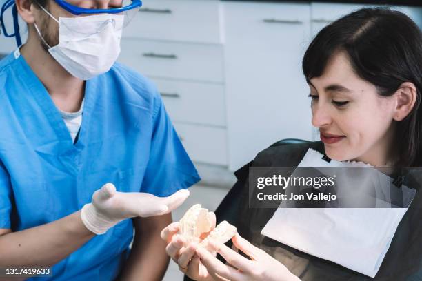 una mujer joven está en la consulta del dentista. el dentista le muestra a la paciente un molde dental. - paciente stock pictures, royalty-free photos & images