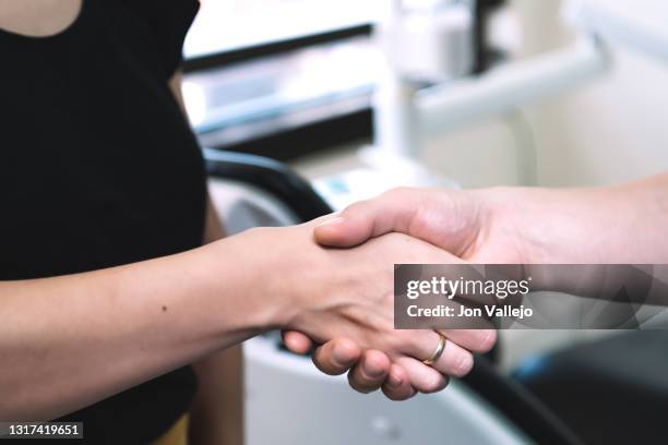 primer plano de la mano de una mujer y de un hombre mientras se dan la mano. son las manos de un dentista y un paciente. - hombre mujer stockfoto's en -beelden