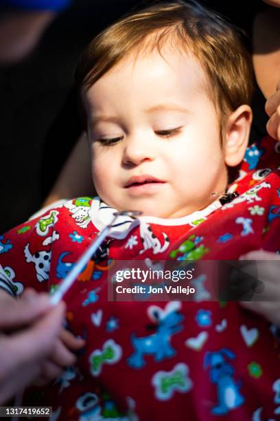 un niño, de menos de dos años, está en la consulta del dentista con una bata roja mientras se mira en un pequeño espejo sostenido por la mano del dentista. - 35 39 años stock pictures, royalty-free photos & images