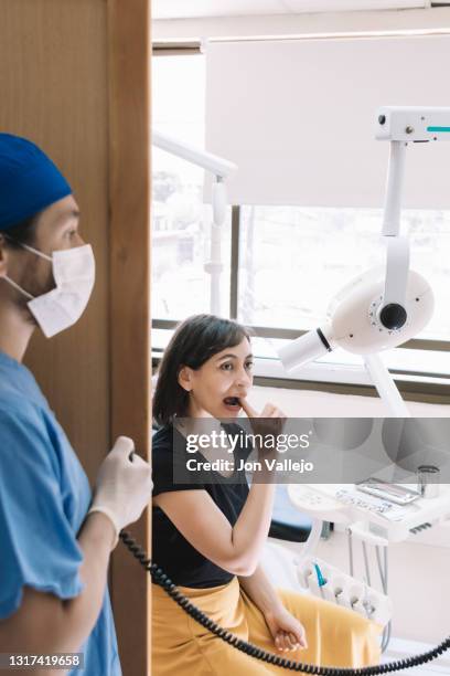 el dentista se coloca detrás de la pantalla de madera para no recibir ningún rayo en su cuerpo cuando hace las placas para el paciente. - paciente stock pictures, royalty-free photos & images