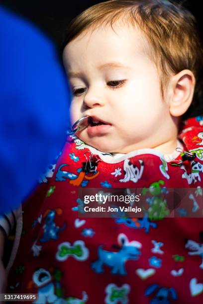 foto vertical de un niño menor de dos años en la consulta de un dentista con bata roja, el dentista está bajando el labio superior del niño con un pequeño espejo para mirar sus dientes mientras el niño mira al dentista. enfoque selectivo. - 35 39 años stock pictures, royalty-free photos & images