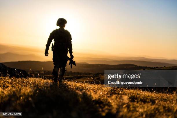 soldado caminando en el campo de batalla al atardecer - army soldier fotografías e imágenes de stock