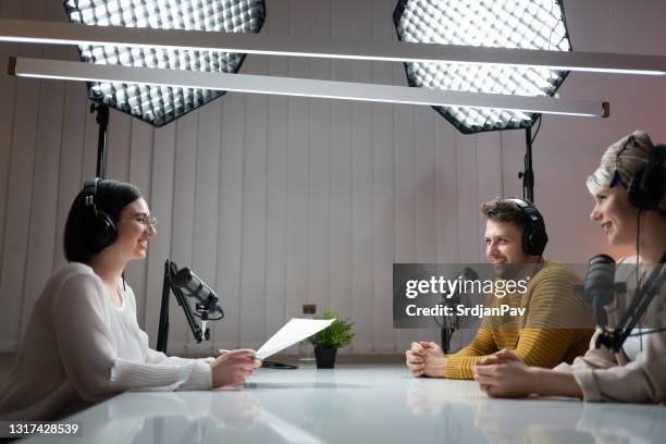 smiling female host interviewing her guests on a talk show - radio dj studio stock pictures, royalty-free photos & images