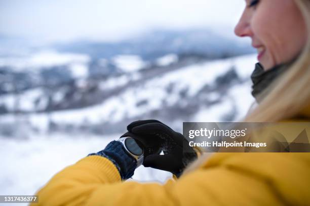 portrait of mid adult woman on a walk in winter nature, using smartwatch. - pedometer stock pictures, royalty-free photos & images