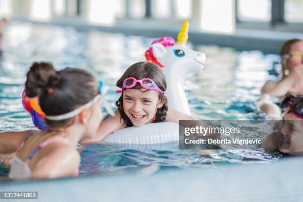 ragazza felice che galleggia in piscina sull'unicorno gonfiabile e parla con i suoi amici - piscina pubblica foto e immagini stock