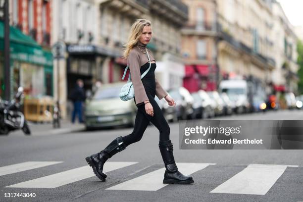 Almuneda Lapique @almulapique wears black leather knee-high long military boots equipped with decorative shin guards, a black bodysuit from & Other...