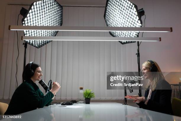 dos mujeres sonrientes hablando y grabando el podcast en un estudio - radio station fotografías e imágenes de stock