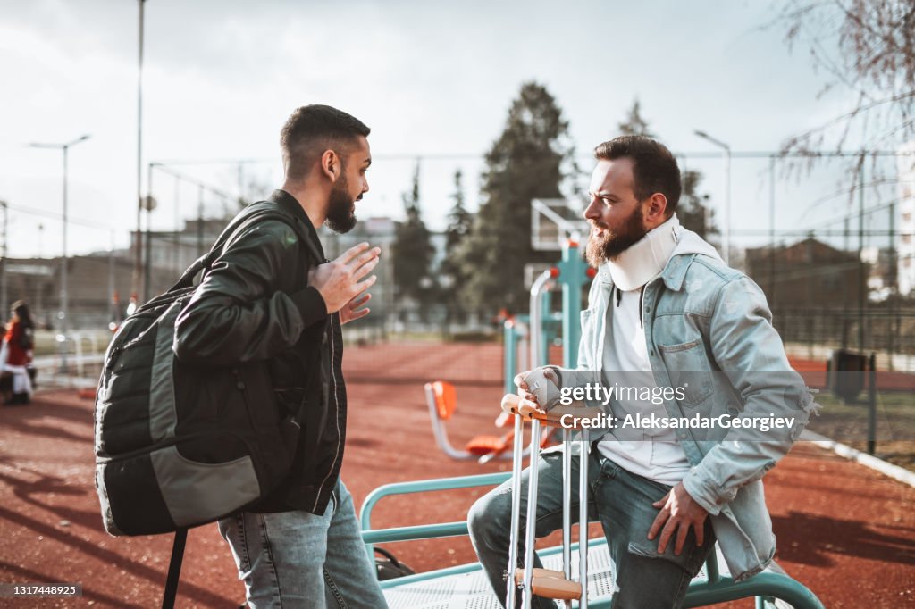 Bully Arguing With Injured Male On Outdoor Sports Field