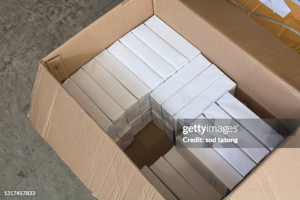 high-angle close-up view of the hands of a manufacturing worker putting packed products, in cardboard boxes before export or shipping during manual work - hands holding open box top view stock pictures, royalty-free photos & images