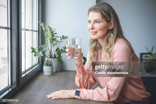 attractive middle aged woman in the office ( drinking water) - mature woman in water stock pictures, royalty-free photos & images
