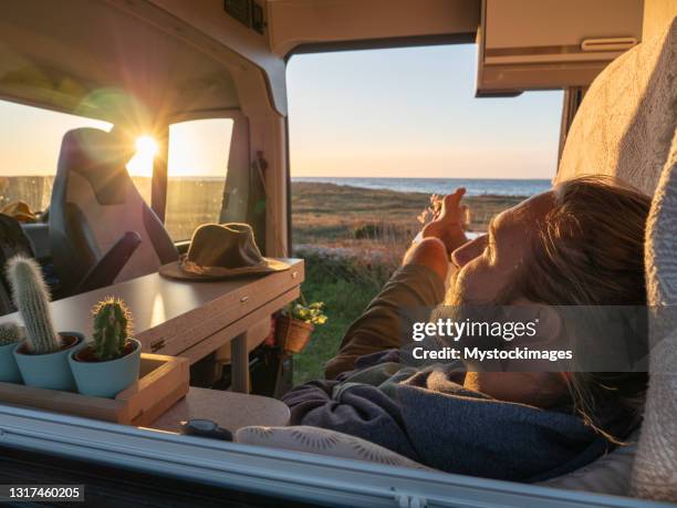 man lying in a van looking at ocean - rv beach stock pictures, royalty-free photos & images