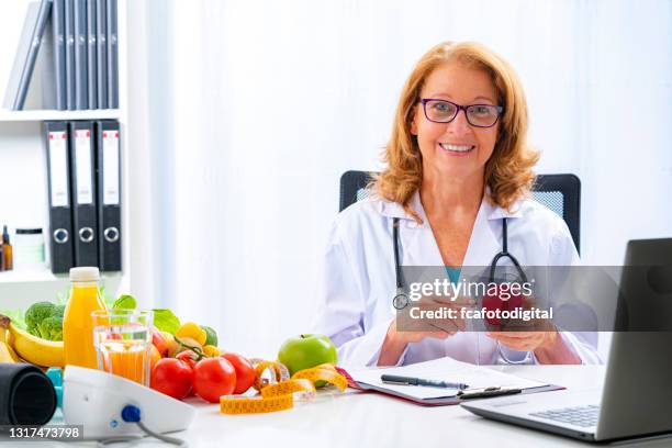 médica sorridente segurando forma de coração vermelho - nutritionist - fotografias e filmes do acervo