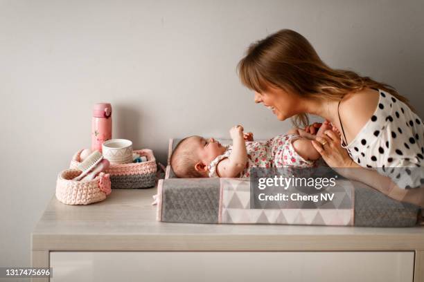 ママ変更赤ちゃんの女の子おむつ - changing diaper ストックフォトと画像