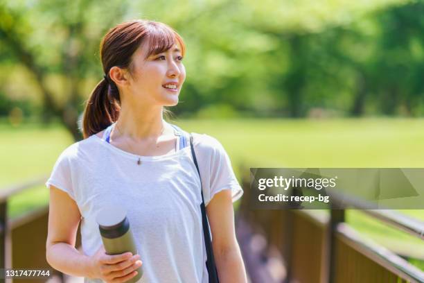 mujer con estera de ejercicios caminando en la naturaleza - mujeres de mediana edad fotografías e imágenes de stock