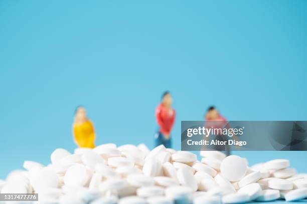 large number of encapsulated pills. in the background there are woman figures (miniature figurines). ( - mdma stock pictures, royalty-free photos & images