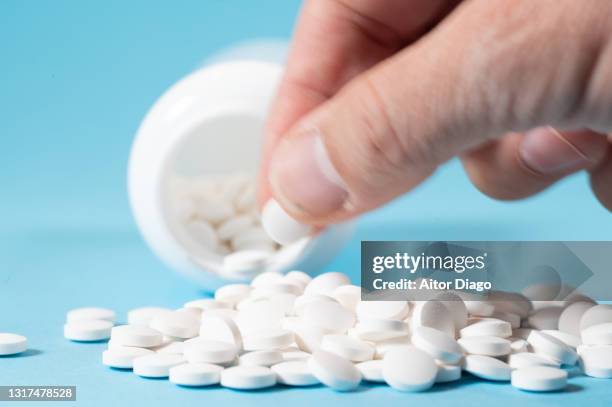 man's hand taking a pill. there is a large number of pills. - medicina para los resfriados fotografías e imágenes de stock