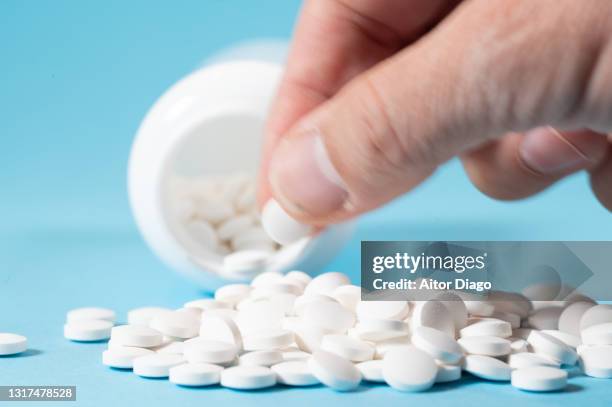 man's hand taking a pill. there is a large number of pills. - acetaminophen - fotografias e filmes do acervo