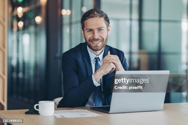 lächelnder geschäftsmann mit laptop - business man at desk stock-fotos und bilder