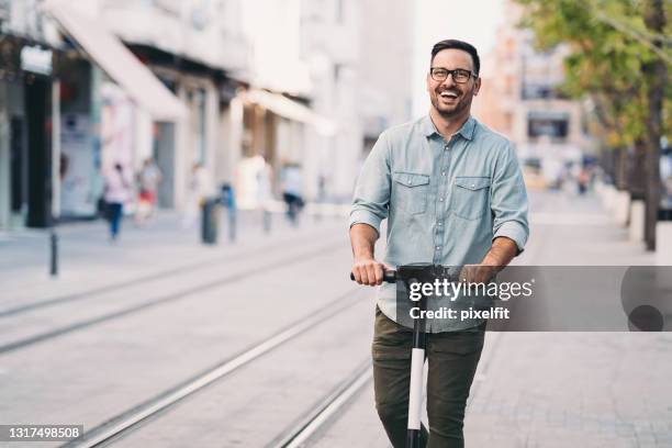 happy man riding an electric scooter in the city - man on scooter stock pictures, royalty-free photos & images