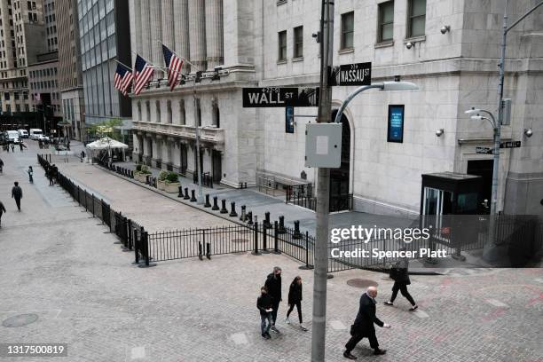 People walk by the New York Stock Exchange after global stocks fell as concerns mount that rising inflation will prompt central banks to tighten...