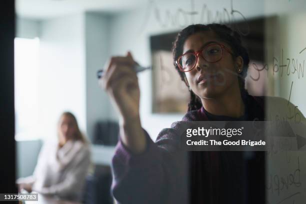 businesswoman writing on glass wall during meeting - strategy foto e immagini stock