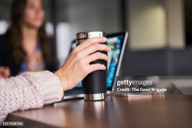 close up of hand holding coffee mug during business meeting - termos fotografías e imágenes de stock