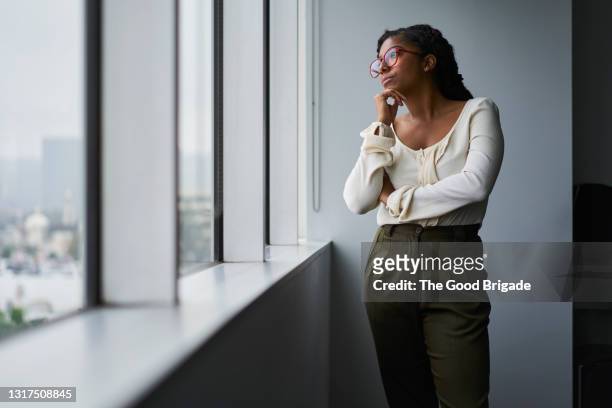 thoughtful businesswoman looking out window in board room - woman thinking hand on chin stock pictures, royalty-free photos & images
