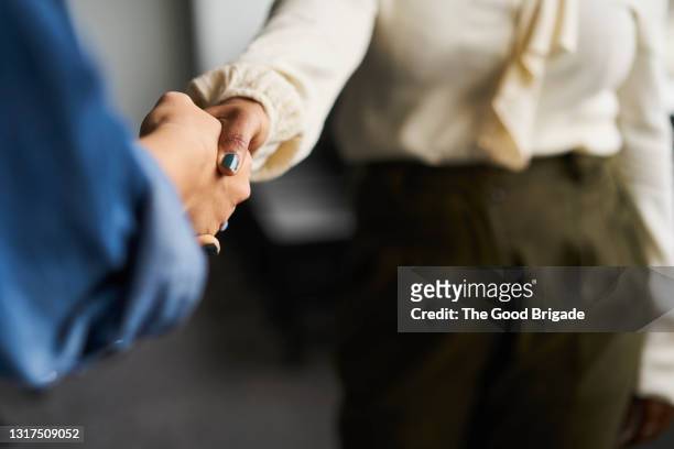 businesswomen shaking hands in conference room - handshake stock-fotos und bilder