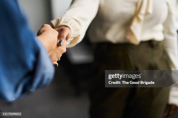 businesswomen shaking hands in conference room - società foto e immagini stock