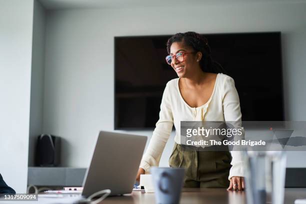 smiling woman leading meeting in conference room - board room meeting stock-fotos und bilder
