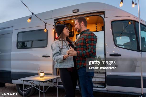 junges paar tanzen und genießen die natur, lichterketten, lagerfeuer und ihre wohnmobil erstellen sie einen romantischen abend - caravan stock-fotos und bilder