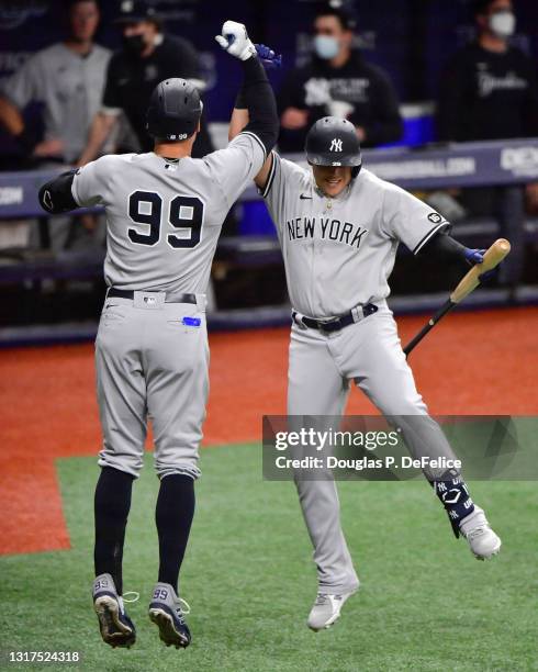 Aaron Judge celebrates with Gio Urshela of the New York Yankees after hitting a solo home run during the first inning against the Tampa Bay Rays at...