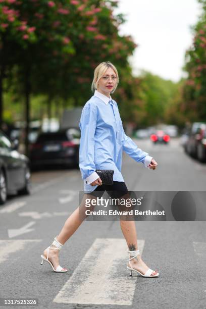 Emy Venturini @sustainably_by_emy wears glasses from Ray Ban, large earrings, a pale pastel blue long shirt with white collar from Burberry, black...