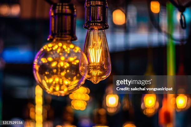 close-up of illuminated light bulbs hanging from ceiling - filamento fotografías e imágenes de stock