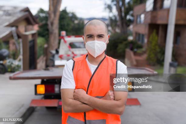 latin american tow truck operator wearing a facemask while towing a car - collision avoidance stock pictures, royalty-free photos & images